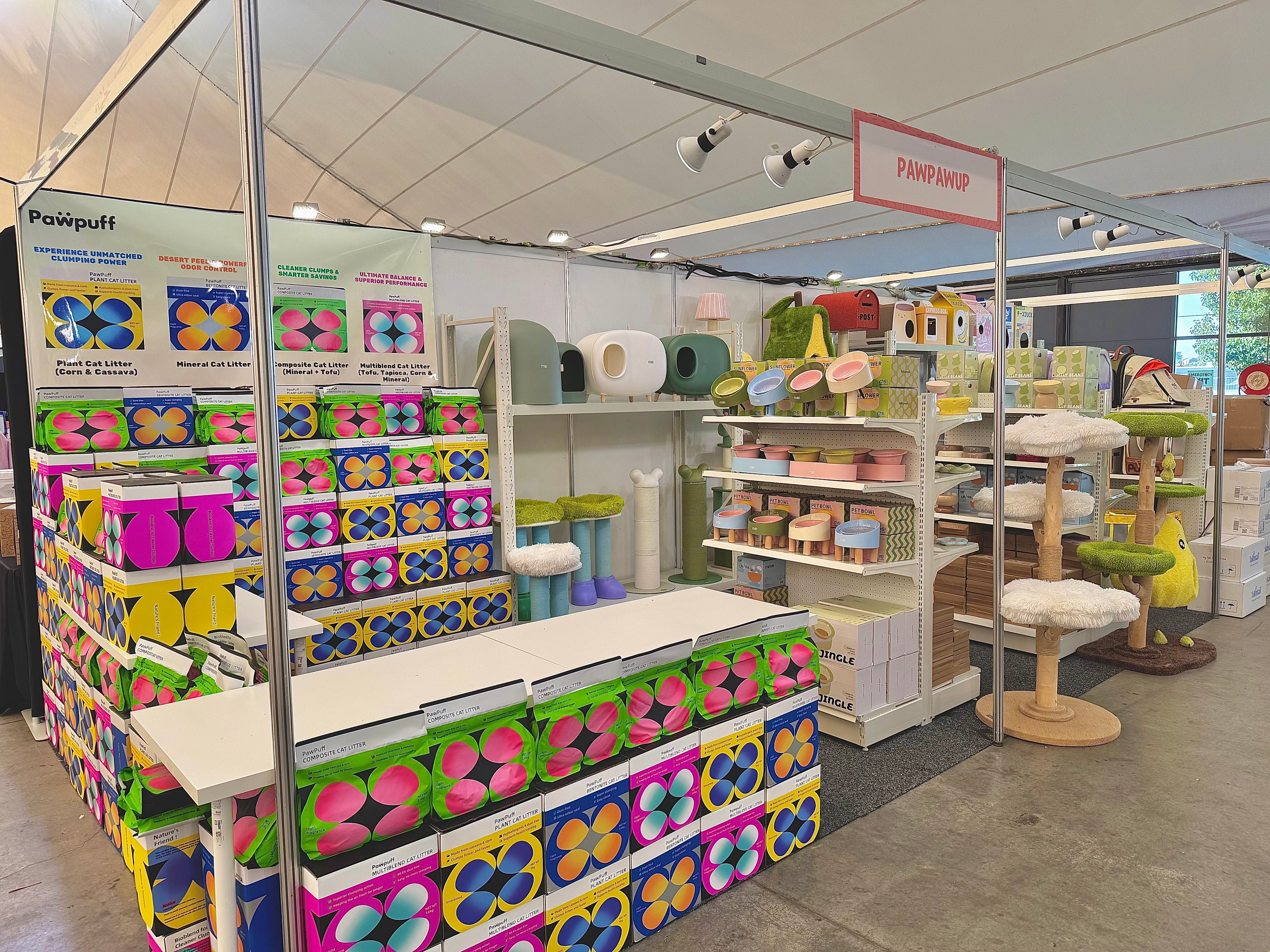 Wide view of a pet store booth displaying cat litter, feeding bowls, and climbing structures as part of their best-selling pet supplies.