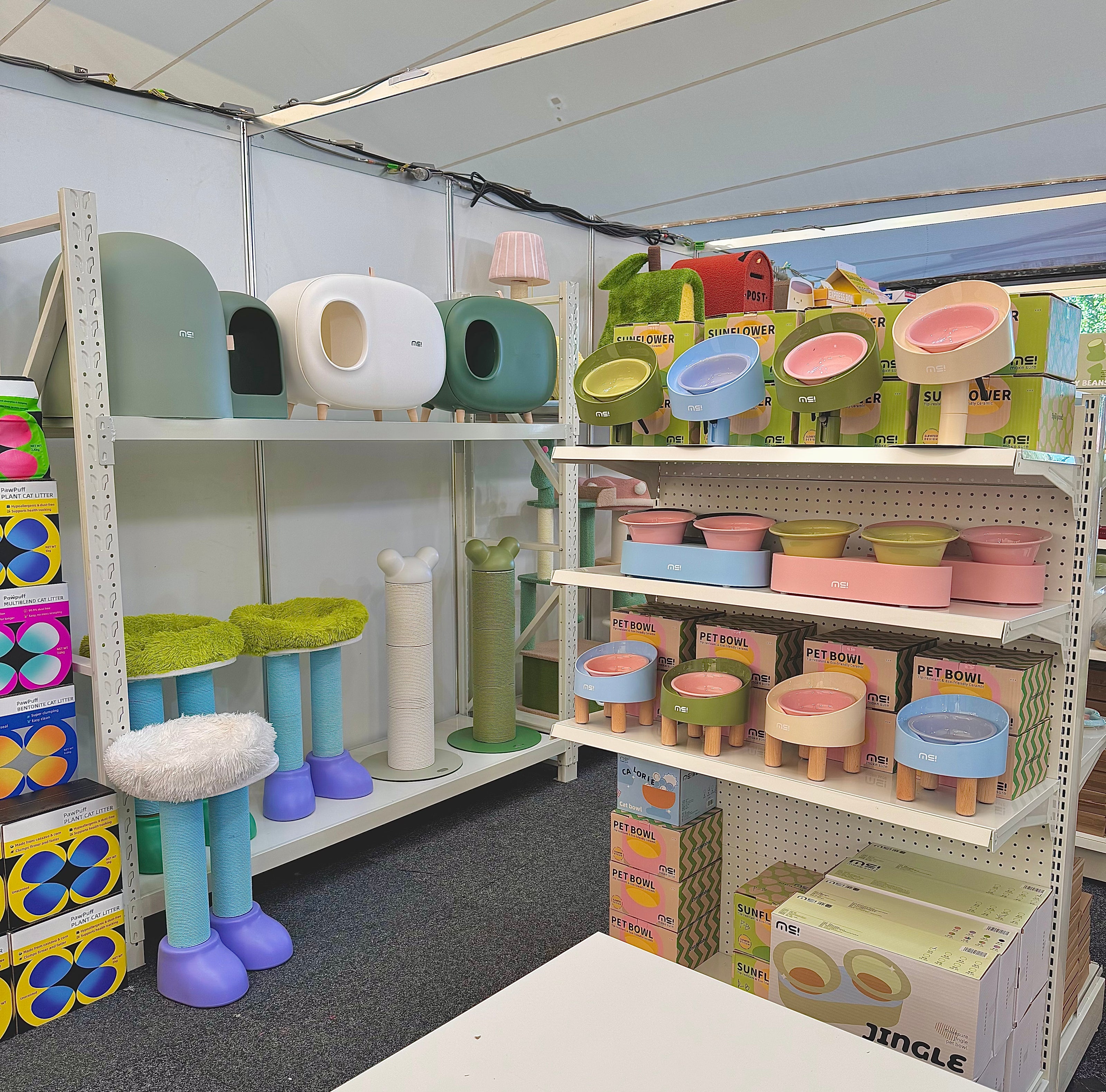 Colorful shelves filled with pet bowls, litter boxes, and scratch posts at a vibrant pet store pop-up featuring premium pet supplies.